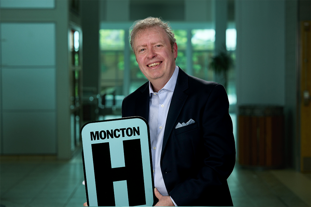 Jason Headshot Holding Moncton H logo