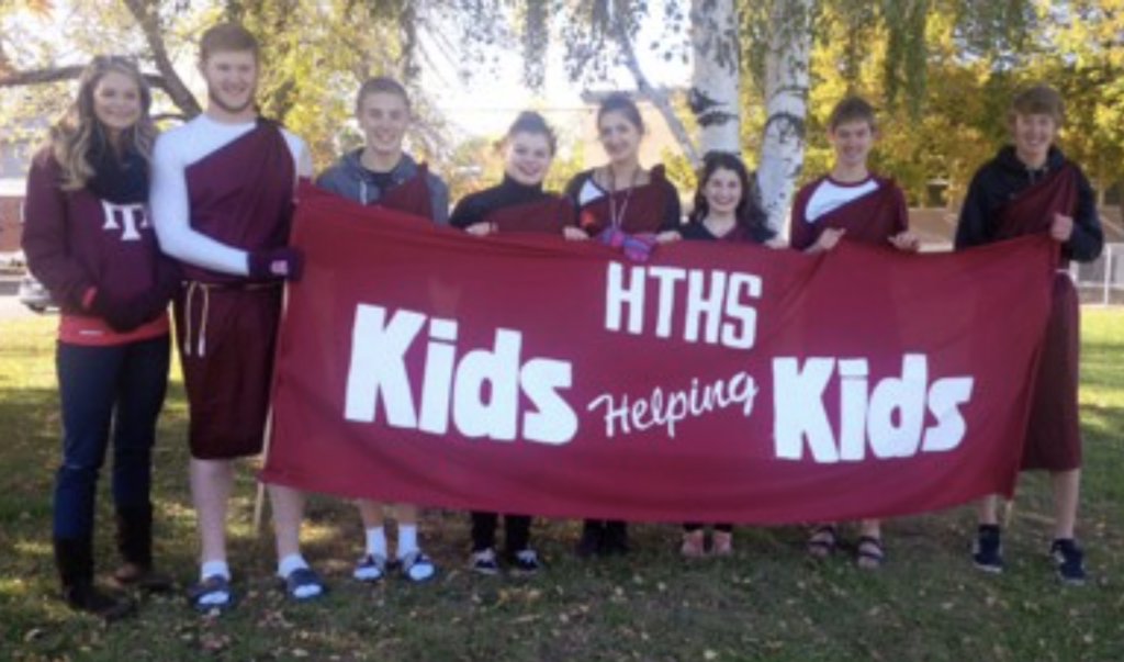High School Students holding banner saying kids helping kids