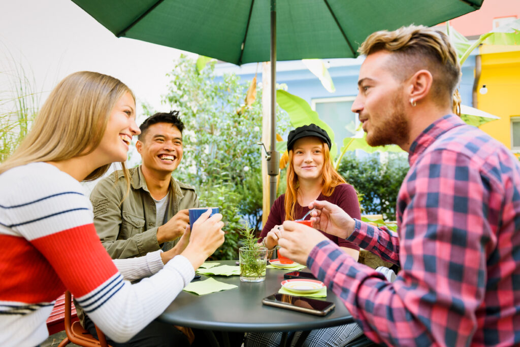Group of 4 smiling people sitting at an outdoor table