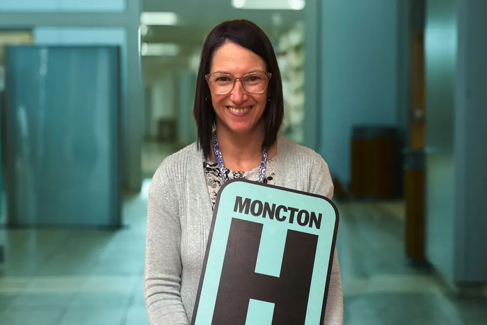 Suzanne Pellerin Holding H Sign and Smiling at camera